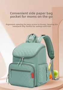 Detail of mint green quilted diaper bag showing side paper pocket and zipper design