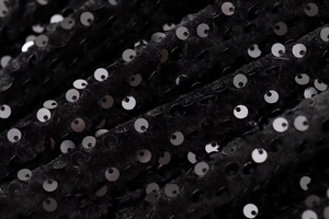 Détail de tissu élégant à paillettes noires sur base velours pour une robe de soirée