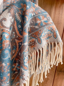 Close-up of blue and orange paisley pattern cashmere-like scarf with woven tassels