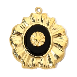 Close-up of gold oval pendant with black inlay and wave-shaped edges on white background