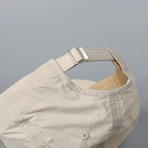 Macro view of beige quick-dry baseball cap featuring an adjustable silver metal buckle