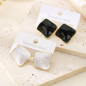 Macro detail of irregular black and white enamel square earrings in stainless steel