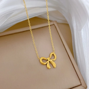 Minimalist gold bow pendant necklace in titanium steel on silk fabric display
