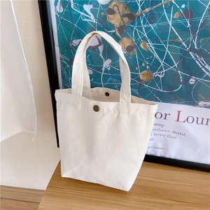 Detail view of a cream canvas lunch bag featuring a secure single metal snap closure