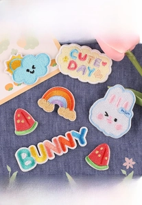 Detail of cute embroidered patches with bunny and rainbow designs on blue fabric