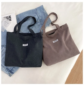 Detailed view of thick canvas tote bags in black and brown with fashion woven labels