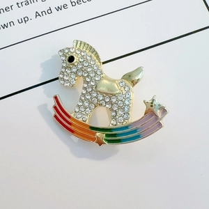 Close-up of rocking horse brooch with white crystals and colorful rainbow bridge detail