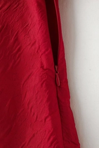 Détail d'une robe rouge avec fermeture éclair invisible et tissu à texture gaufrée