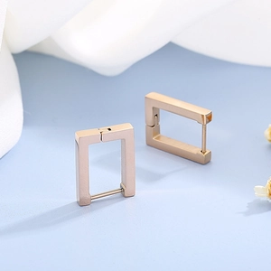 Minimalist gold geometric rectangular hoop earrings displayed on white fabric background