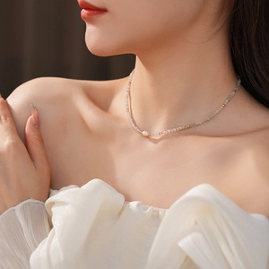 Detail of freshwater pearl necklace with grey mineral beads on model's neck