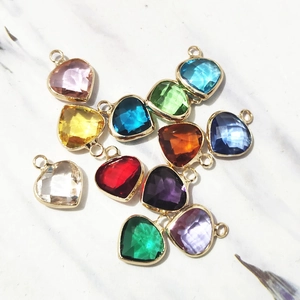 Macro detail of colorful heart birthstone pendants with gold plated metal frames for DIY