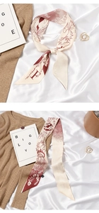 Detail of a beige skinny silk scarf with vine patterns tied on a white fabric background