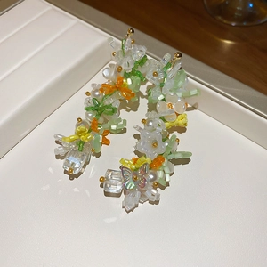 Detailed view of handmade beaded flower earrings with green, white, and orange accents