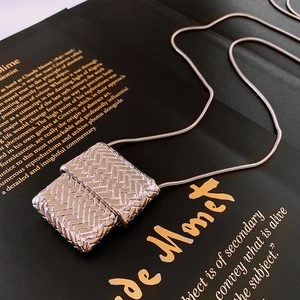 Macro shot of silver woven square pendant necklace with polished metallic texture