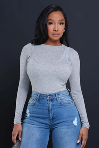 Detailed view of high-waist blue ripped jeans paired with a grey ribbed knit long sleeve sweater