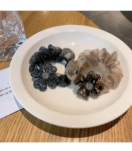 Detail of organza scrunchies with large rhinestone flower on a white ceramic plate
