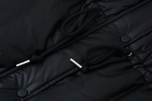 Detailed close-up of glossy black fabric with metal drawstrings and matte black buttons