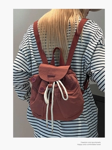 Minimalist reddish-brown nylon drawstring backpack for women featuring front utility pockets