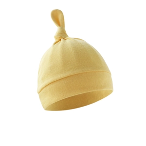 Close-up of yellow cotton newborn baby hat with soft knotted top and ribbed cuff detail