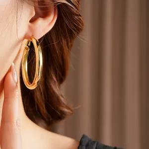 Polished gold round hoop earrings shown on a model for a minimalist fashion look