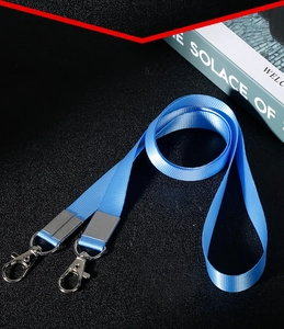 Blaues Schlüsselband mit zwei Metallkarabinern, ordentlich auf dunklem Grund aufgerollt