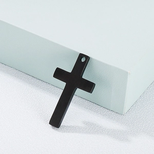 Détail d'un pendentif croix en acier titane noir mat sur une surface texturée