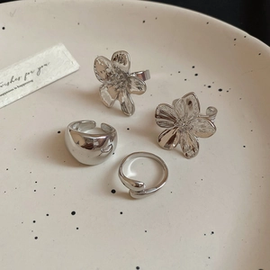 Detailed top view of silver flower rings and metal bands on a ceramic display plate