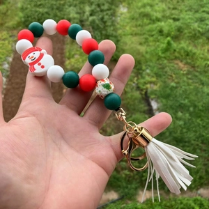 Detail of Christmas beaded keychain with snowman charm and white tassel on green grass