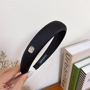 Detailed shot of black fabric headband with silver jewelry inlay and Hand Made label