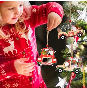 Little girl holding a wooden Christmas truck ornament next to a decorated festive tree