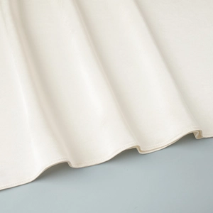 Detailed view of cream-colored satin fabric edge with high-quality flat-seam stitching