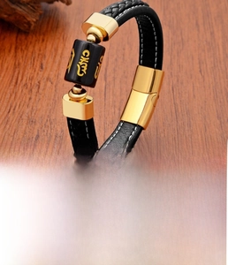 Detail of men's braided leather bracelet with golden Mantra charm on wooden surface