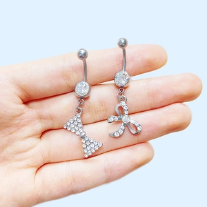 Piercing nombril argenté avec pendentif nœud et zircons blancs sur fond bleu clair