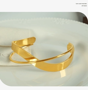 Detail view of a minimalist golden irregular open bangle with mirror-polished finish