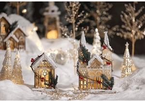 Close-up of wooden Christmas village house with warm LED lights and snowy details