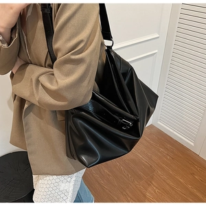 Détail d'un grand sac cabas en cuir souple noir porté à l'épaule sur un mannequin