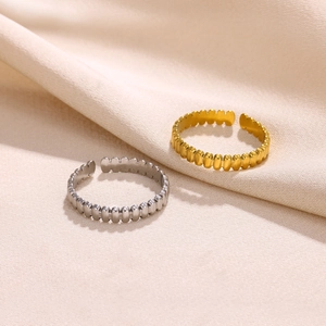 Close-up of adjustable gear-textured open rings in gold and silver finishes on fabric