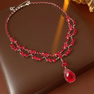 Close-up of luxury silver necklace with red pear-cut zircon and layered tassel design