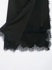 Dettaglio di una gonna in raso nero con pizzo elegante e bordo ondulato rifinito