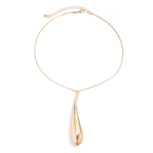 Close-up of a polished gold teardrop pendant on a delicate snake chain necklace