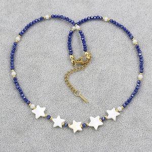 Detail of blue crystal beaded necklace with pearls and white star charms on gray fabric