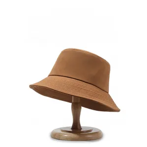 Detail of tan cotton bucket hat with parallel stitching on brim on wooden stand
