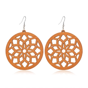 Detailed view of geometric hollowed-out brown wooden earrings with mandala patterns