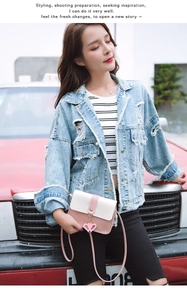 Detail of a pink and white patchwork crossbody bag featuring golden heart pendants