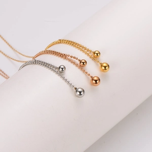 Detailed view of three minimalist metal beaded necklaces in gold, silver, and rose gold finishes