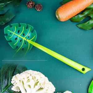 Leaf-shaped slotted spoon for pasta and vegetables in a green kitchen setting