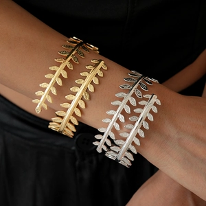 Close-up of golden leaf-shaped adjustable arm cuffs with detailed vein patterns on skin
