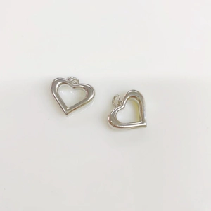 Macro shot of silver hollow heart-shaped charms with polished metal surface and ring loop