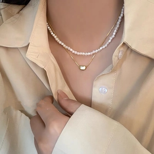 Gros plan sur un collier double rang plaqué or avec perles et pendentif cœur