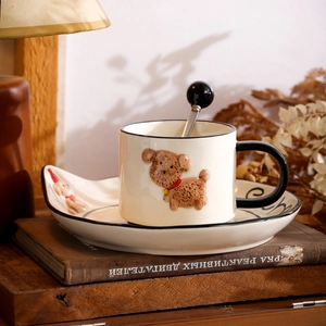 Detailed view of beige ceramic mug with 3D dog relief and black handle on matching saucer
